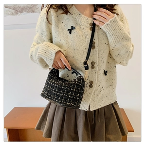 Detail of tweed underarm bag with black leather handle and woven yellow texture