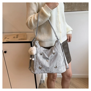 Silver wrinkled leather tote with butterfly metal charms and a plush bear pendant
