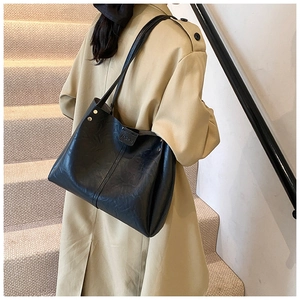 Detail of the black PU leather tote bag showing a sleek side view and gold rivet accents