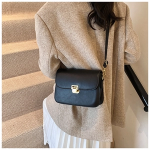Minimalist black leather crossbody bag with gold metallic clasp on a stylish model