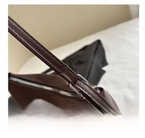 Gros plan sur la boucle métallique et les coutures soignées du sac cabas en cuir brun