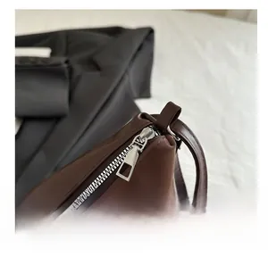 Détail de la fermeture éclair en métal argenté sur un sac fourre-tout en cuir marron foncé