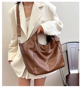Detail of soft brown PU leather hobo tote bag featuring wide shoulder strap and silver hardware