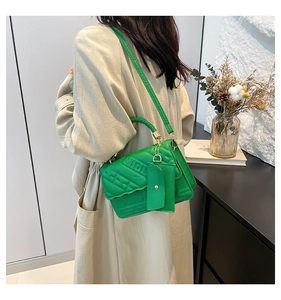 Detail of green quilted crossbody bag with FASHION embossing and mini pouch charm
