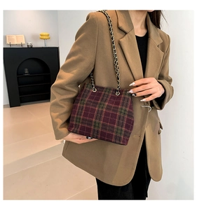 Detailed view of checkered wool bucket bag with gold chain strap on a model
