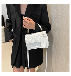 Detail of white quilted handbag with FASHION embossment and small accessory pouch