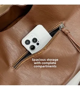 Close-up of brown tote bag side pocket with zipper showing spacious storage for a phone