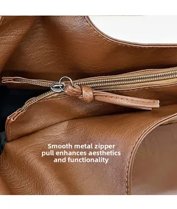 Close-up of polished gold-tone metal zipper and brown leather pull on a large tote bag