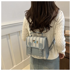 Detail of light blue striped backpack with cute dachshund embroidery and leather buckle straps