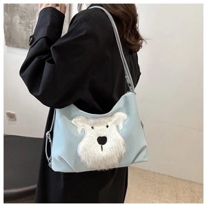 Detail shot of light blue tote bag with a white plush dog patch on a casual outfit