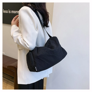 Detail view of large black nylon crossbody bag with fashion strap on a female model