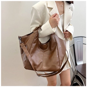 Detail of a large dark brown PU leather tote bag with handles and an adjustable shoulder strap