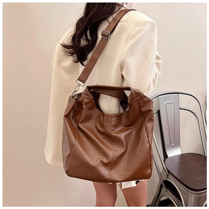 Detail of dark brown faux leather tote bag with adjustable wide strap on model