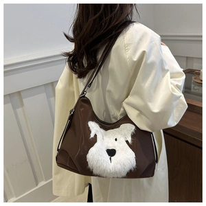 Détail d'un grand sac hobo marron avec applique de chien en peluche sur cuir lisse