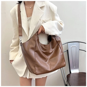Close-up of a large brown leather tote bag styled with a white blazer for a chic look