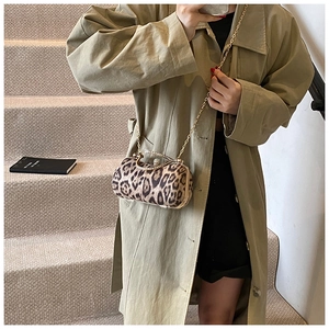 Detail of leopard print clutch with rhinestone handle and gold chain on beige steps