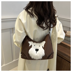 Detail of a brown leather tote bag featuring a plush white schnauzer dog design