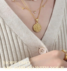 Détail d'un collier doré double épaisseur avec pendentif lotus en relief et charme triangle
