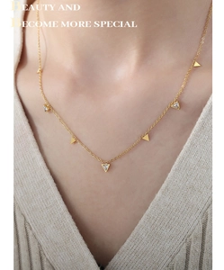 Détail d'un collier doré avec pendentifs triangles en zircon porté par un mannequin chic