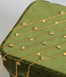 Vue macro d'un collier doré multicouche avec des pendentifs triangulaires en zircon