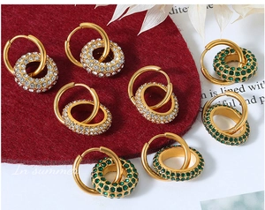 Close-up of 18k gold layered hoop earrings with pavé-set green and white crystals