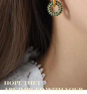 Close-up of gold-plated hoop earrings featuring vintage green crystal pavé setting