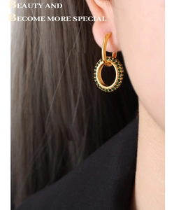 Detail of double-layer gold hoop earrings with green sparkling stones on ear