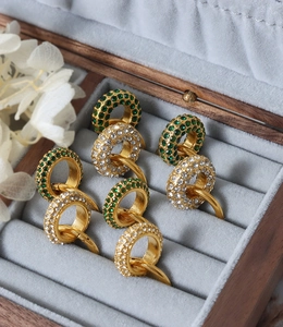 Detail of vintage gold plated hoops with pavé set green and clear crystals in a display box