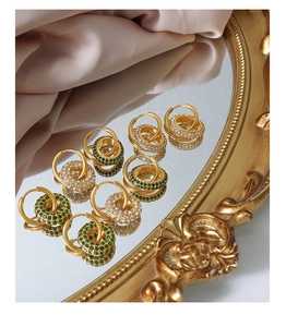 Elegant gold-plated hoop earrings featuring emerald green and clear zircon inlays on a mirror