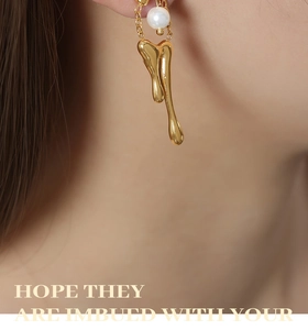 Detalle de pendientes de metal líquido dorado con perla blanca en el modelo
