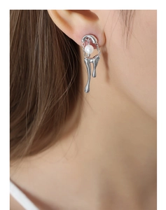 Primer plano de pendientes de metal líquido con perla blanca y cadena en modelo