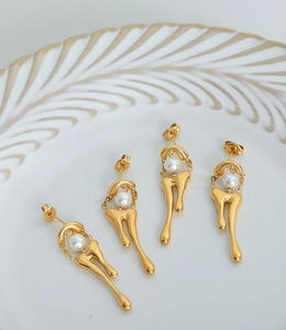 Detalle de pendientes de metal fundido dorado con una perla blanca brillante incrustada
