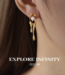 Detalle de pendientes de oro fundido con cadena y perla blanca en la oreja del modelo