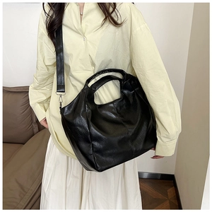Chic black glossy PU leather tote bag shown on model with adjustable shoulder strap