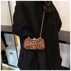 Fashionable leopard print chain clutch bag with gold strap styled on a black blazer