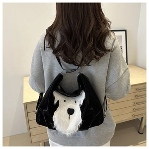 Détail d'un sac en cuir noir avec tête de chien blanche portée par un mannequin