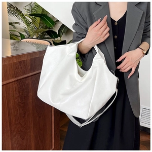 Detailed view of a white PU leather hobo bag with natural texture shown on a shoulder