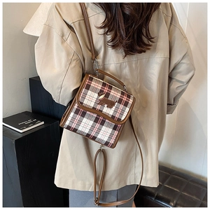 Detail view of plaid crossbody bag featuring a cartoon puppy patch and brown PU leather trim