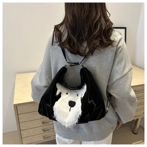 Detail of glossy black tote bag with white plush puppy patch and zipper closure