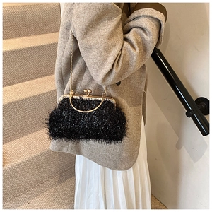 Detail of black faux fur evening clutch bag with gold chain and plush velvet texture