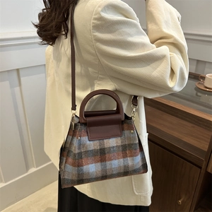 Sac à main vintage à carreaux avec poignées en cuir marron porté avec un blazer beige
