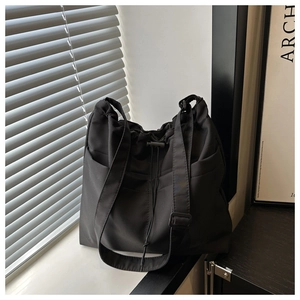 Detail view of a black nylon drawstring tote bag with spacious side pockets for daily use