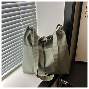 Detailed side view of sage green nylon tote bag with white stitching and drawstring design
