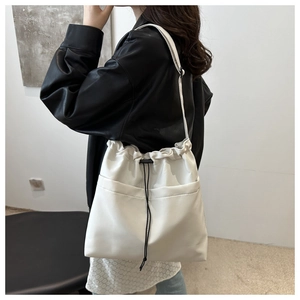 Detail of white drawstring tote bag with black cords showing side pocket on a model