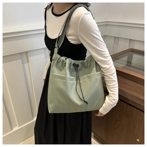 Large pale green nylon bucket bag with drawstring closure and large front pockets for women
