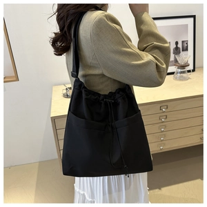 Detail view of a black nylon drawstring tote bag with functional pockets for daily use