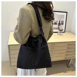 Black cargo tote bag with drawstring closure and large front pockets worn on shoulder