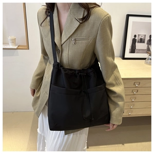 Detail shot of black nylon drawstring bucket bag with large pockets and shoulder strap