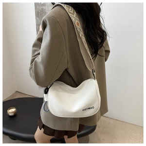 Side view of white crescent bag with geometric jacquard strap worn by a model