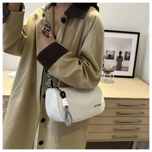 Detail of white cylindrical canvas crossbody bag with wide geometric woven shoulder strap